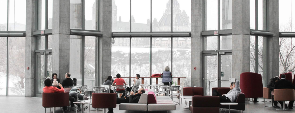 Sitting at tables and chairs in a large building