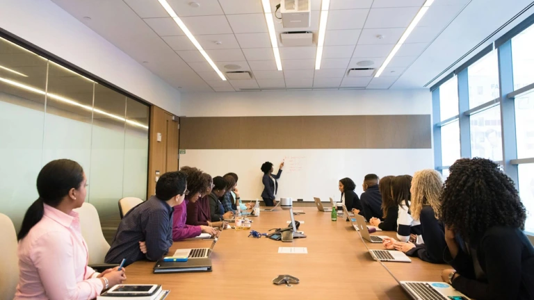 A woman talking at a whiteboard in a board meeting