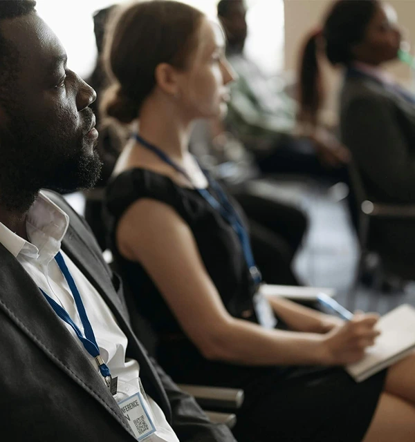 A man and woman sitting in a meeting listening