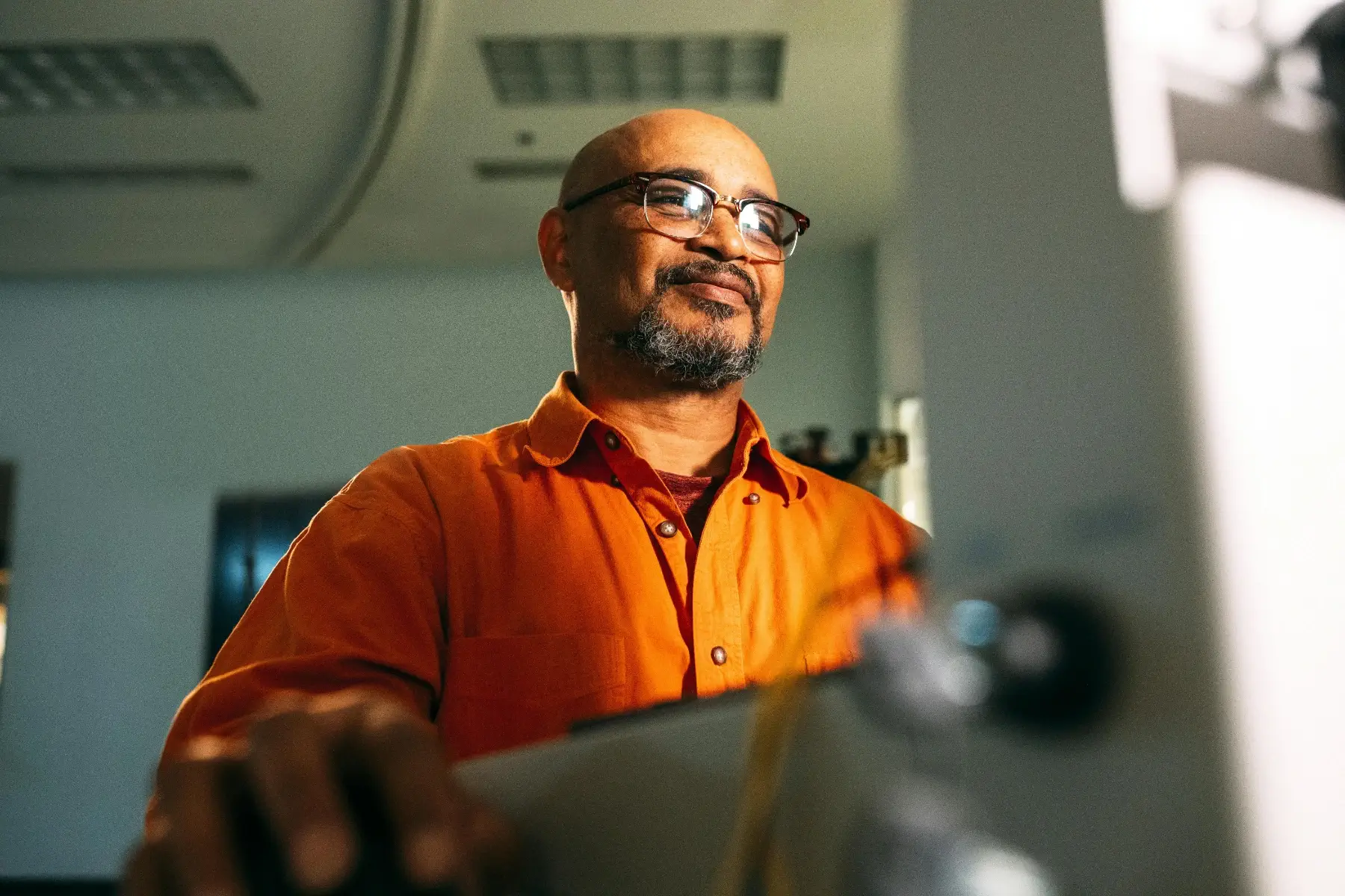 A man in an orange shirt working at machinery